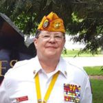 Department officer - Commandant - Marine Corps League member in uniform with cover and medals with trees behind her.